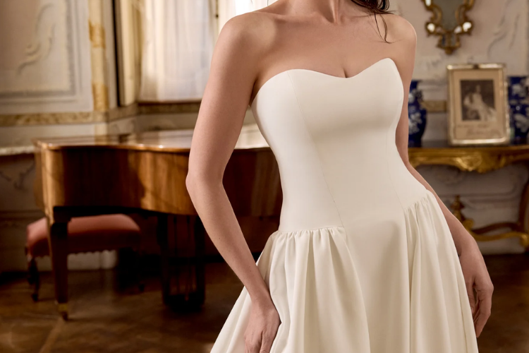 Bride wearing a strapless sweetheart wedding gown with a fitted bodice and softly gathered skirt in a formal interior setting.